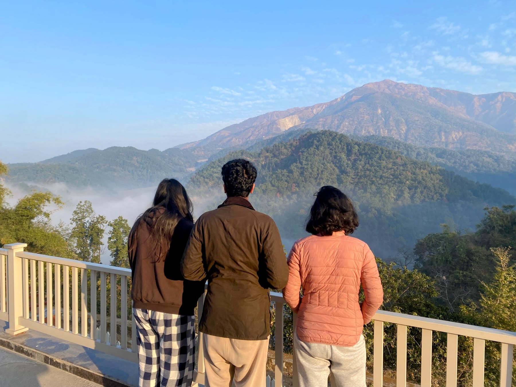 Three guests standing quietly on Amatā's balcony and looking towards the mountains